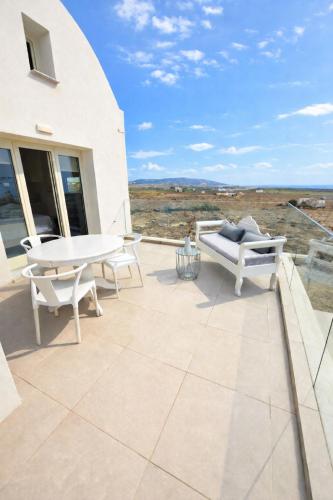 a patio with a table and a bench on a building at Apeiron Akrotiri - Apeiron Hotels in Akrotiri