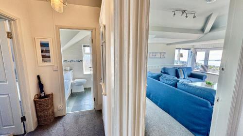 a living room with a blue couch and a bathroom at HEADLANDS-2 BED-SEA VIEW APARTMENT-TREARDDUR BAY in Trearddur
