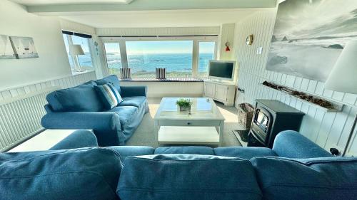 a living room with blue furniture and a view of the ocean at HEADLANDS-2 BED-SEA VIEW APARTMENT-TREARDDUR BAY in Trearddur