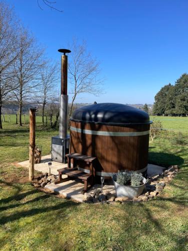a large wooden barrel with a picnic table and a bench at Gite La Chouette met hottub in Beyssac