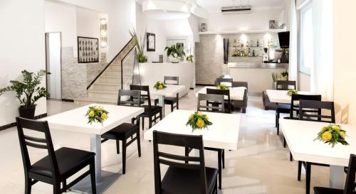 a restaurant with white tables and black chairs at Hotel Ferrara in Cattolica