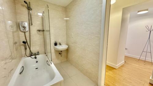 a bathroom with a tub and a sink and a shower at 24 CLIFF APARTMENT-3 BED-GROUND FLOOR-SEA VIEWS in Trearddur