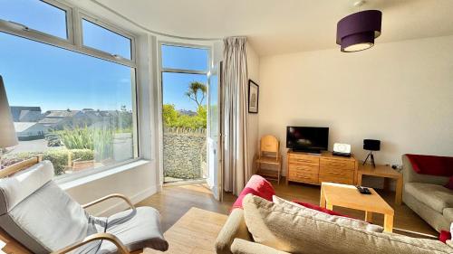 a living room with a couch and a tv and a window at 24 CLIFF APARTMENT-3 BED-GROUND FLOOR-SEA VIEWS in Trearddur