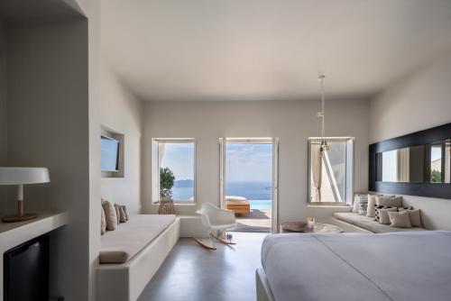 a bedroom with a large bed and a living room at West East Suites in Imerovigli
