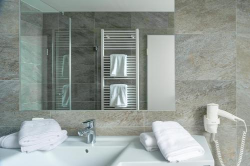 a bathroom with a sink and a mirror and towels at BSW Ferienwohnungen Brockenblick in Schulenberg im Oberharz