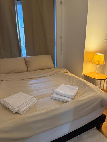 a white bed with two towels on top of it at appartement cosy Paris 17eme in Paris