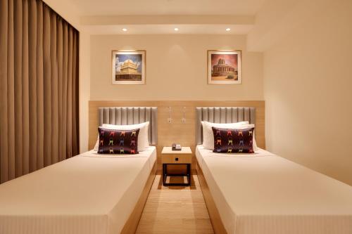 a hotel room with two beds and a side table at Keys Prima by Lemon Tree Hotels, Whitefield, Bengaluru in Bangalore