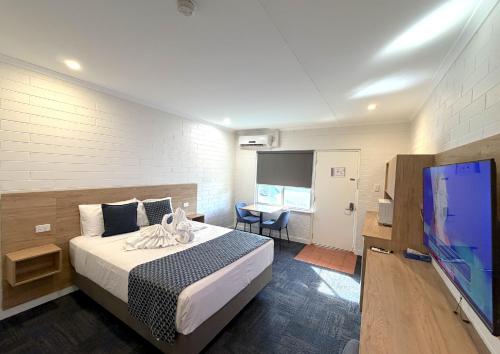 a bedroom with a bed and a flat screen tv at Katherine Motel in Katherine