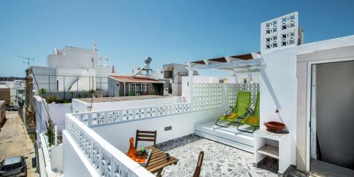 a balcony with chairs and tables on a building at KASA BLANCA in Olhão