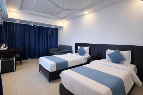 a hotel room with two beds and a desk at Hema's Hotel Supreme in Visakhapatnam