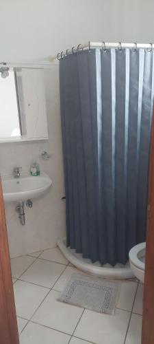 a bathroom with a blue shower curtain and a sink at Castello Azzurro in Agia Anna Naxos