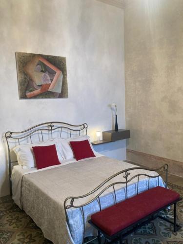 a bedroom with a bed with red pillows and a painting at Palazzo Cariddi Apartment in Nardò