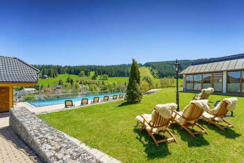 a group of chairs sitting in the grass near a pool at Hotel Schlehdorn in Feldberg