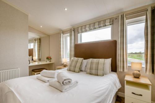a bedroom with a large white bed with towels on it at Primrose 2 bed - Violet in Eye