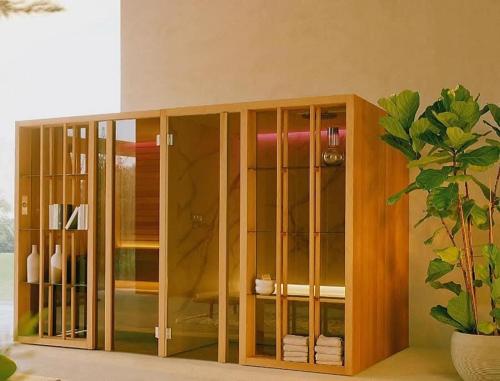 a wooden cabinet with glass doors next to a potted plant at Beach Club Ippocampo in Ippocampo