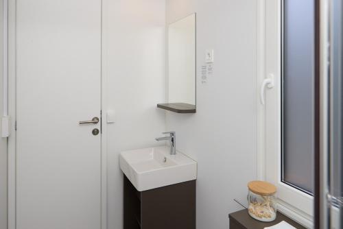 a white bathroom with a sink and a mirror at Luxury Homes Pašman in Pašman