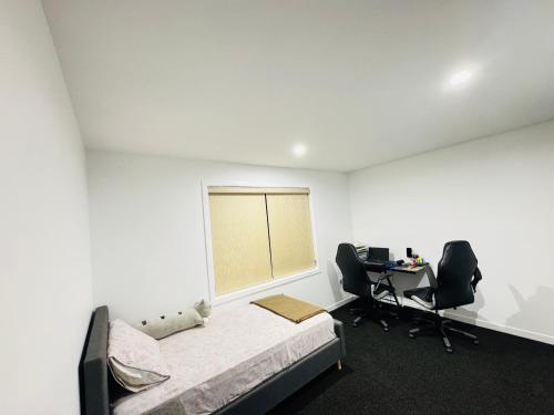 a bedroom with a bed and two chairs and a desk at TheQuietPadRest Easy Fly Easy in Christchurch