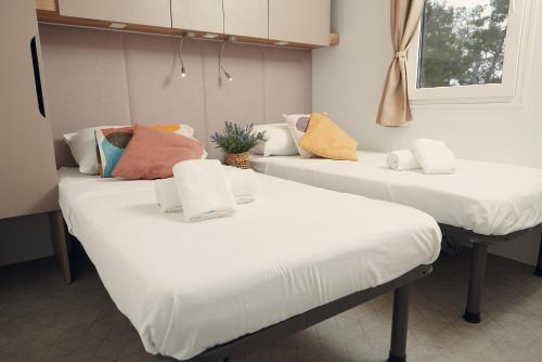 two beds in a room with white sheets and colorful pillows at Luxury Homes Pašman in Pašman