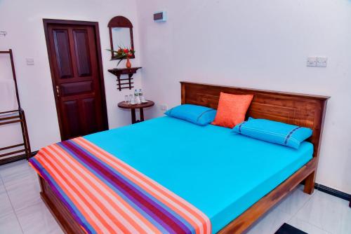 a bedroom with a wooden bed with colorful pillows at Maiya Wild Ship Villa in Kosgoda
