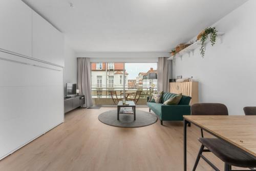 a living room with a table and a green couch at Lilyta B201 in De Haan
