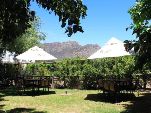 two tables and chairs with umbrellas in a yard at The Barn On 62 - Cottages in Montagu