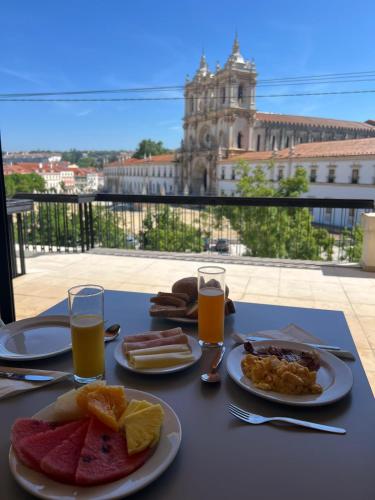 a table with plates of food and glasses of orange juice at Hotel Santa Maria in Alcobaça