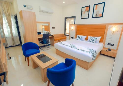 a hotel room with a bed and a desk and chairs at Vitash Inn in Tirupati