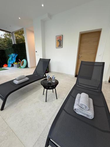 two black beds in a living room with a table at Studio de Charme Paris in Rocquencourt