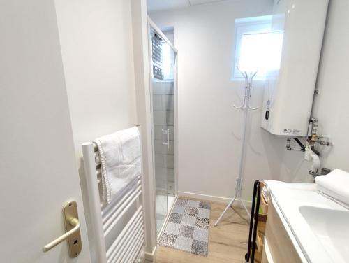 a white bathroom with a shower and a sink at Yvéro in Quend-Plage