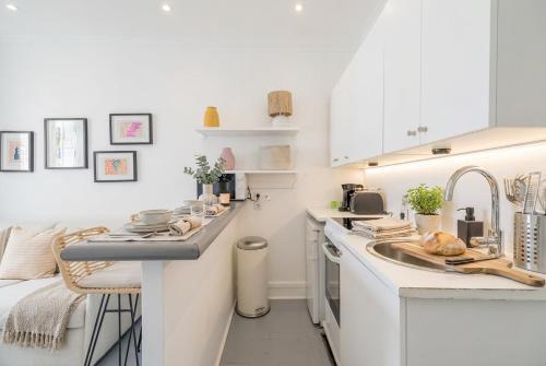 a white kitchen with a sink and a counter at FurtiveStay - Les Sablons - Orléans in Neuilly-sur-Seine