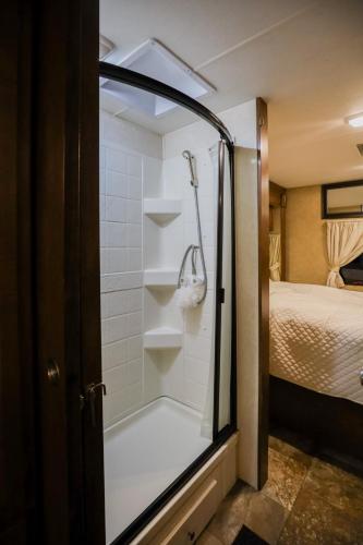 a walk in shower in a room with a bed at Kamper 30m2 max 4 osoby in Ciężkowice
