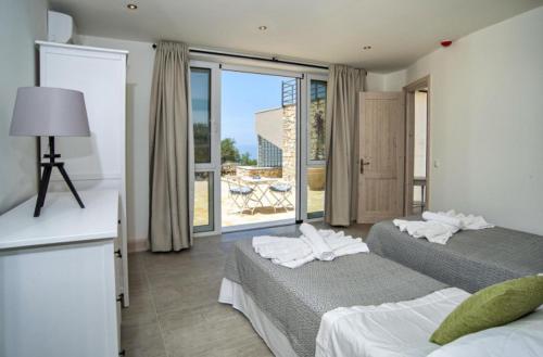 a bedroom with two beds and a large window at Villa Alexa in Gaios