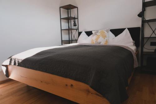 a bed with a black blanket and white pillows at Pannolio Beach Boutique Apartment in Eisenstadt