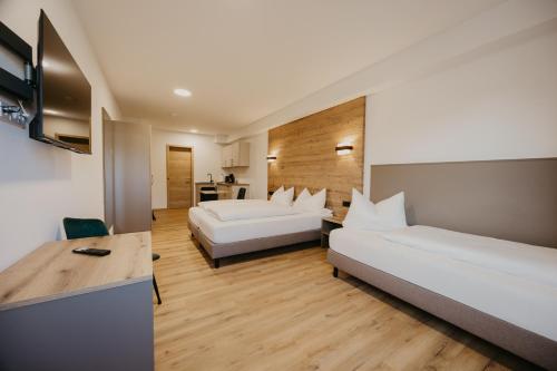 a hotel room with two beds and a desk at Schmitt Bräu - Hotel und Brauereigasthof in Scheßlitz
