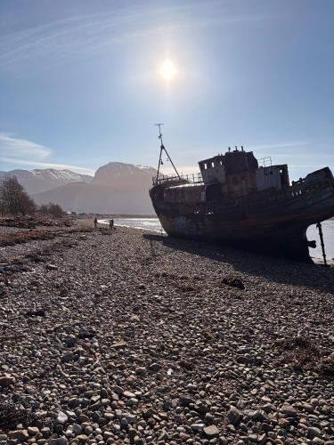 an old boat sitting on a rocky beach at Inas Place in Caol