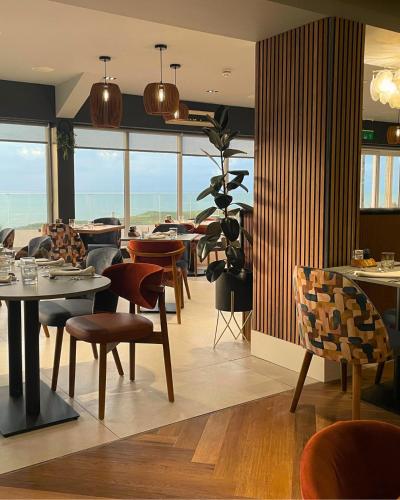 a dining room with tables and chairs and windows at The Cliff Hotel & Spa in Cardigan