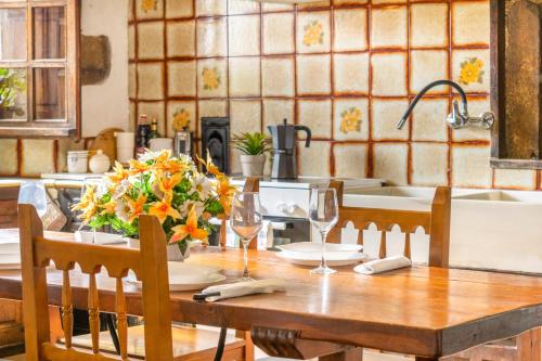 a kitchen table with a vase of flowers and wine glasses at Casa Arozenia, Hogar rústico en pleno valle Ulzama in Lizaso
