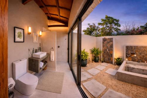 a bathroom with a tub and a toilet and a sink at Vanilla Lodge Tropical Garden Suite with Outdoor Stone Bath & Bamboo Shower, inifinity pool in Cap Malheureux