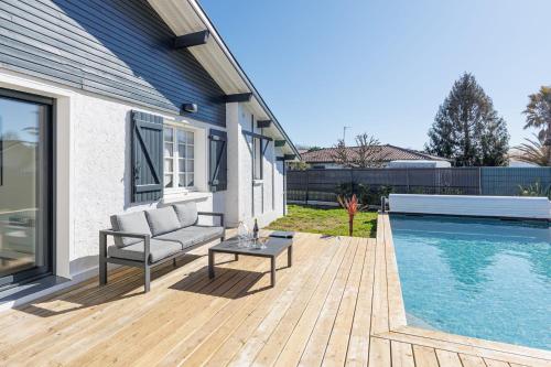 a patio with a couch and a table next to a pool at Villa Blue Pool - Welkeys in Seignosse