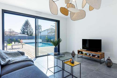 a living room with a couch and a tv at Villa Blue Pool - Welkeys in Seignosse