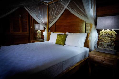 a bedroom with a large bed with a canopy at Alam Taman Villa in Tabanan