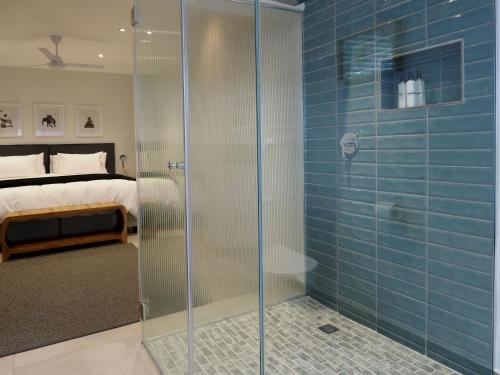 a glass shower in a bedroom with a bed at Waterland Lodge in Hout Bay