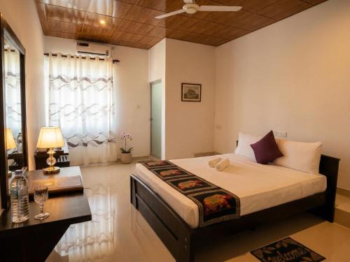 a bedroom with a bed and a table and a window at Aqua Hotel Yala in Yala