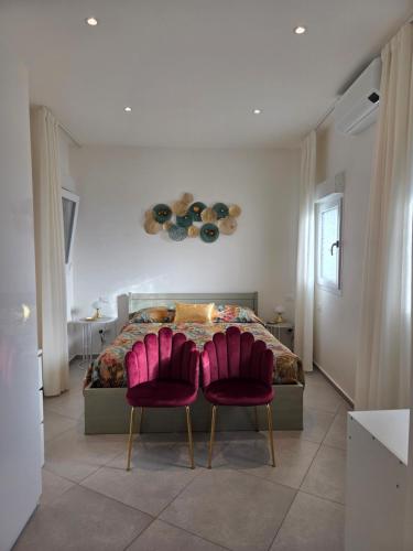 a bedroom with a bed and two pink chairs at Appartamento Teodorico Ravenna in Ravenna