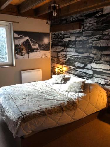 a bedroom with a stone wall and a bed at Le CHALET in Gérardmer