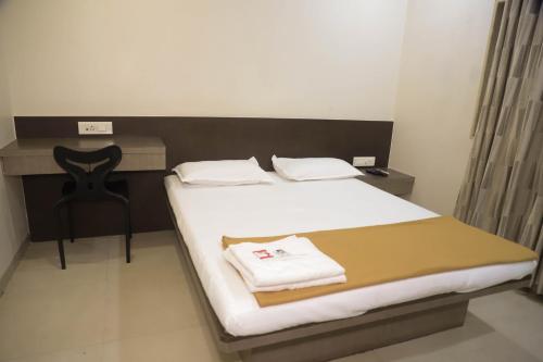 a bedroom with a bed with a desk and a chair at Hotel Maharaja in Thane