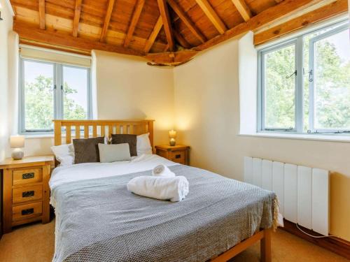 a bedroom with a bed and two windows at 3 Bed in Launceston oc-88858 in Saint Giles on the Heath
