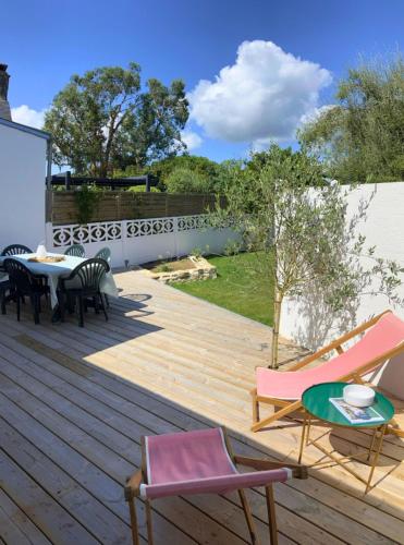 a wooden deck with chairs and a table on it at Superbe maison 85m2 - Plages à 2km - Jardin clos - Maison Kaerell in Billiers