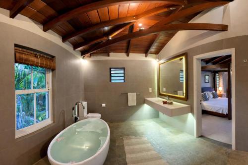 a bathroom with a tub and a sink and a bed at Cinnamon Room Four-Poster Bed, Freestanding Bath, Walk-In Shower & Infinity Pool in Cap Malheureux