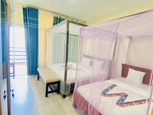 a bedroom with two beds and a canopy bed at Amara Kivu Resort in Île Bugarura